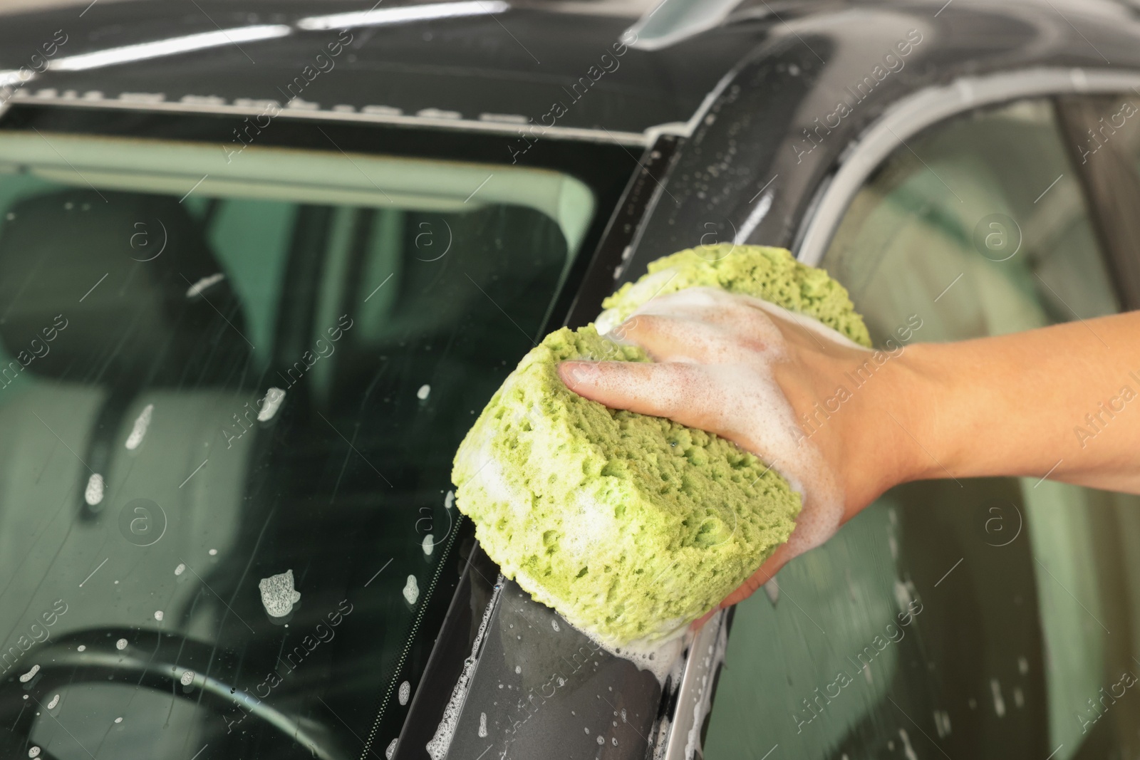 Photo of Man washing auto with sponge at car wash, closeup