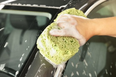 Photo of Man washing auto with sponge at car wash, closeup