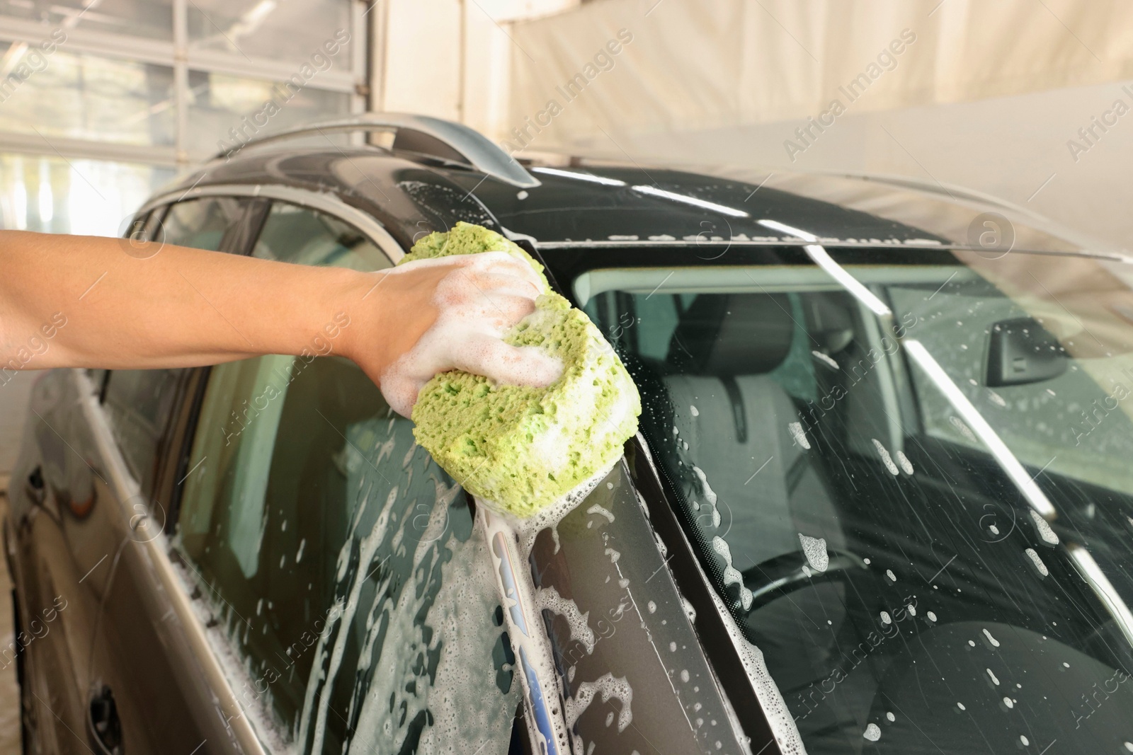 Photo of Man washing auto with sponge at car wash, closeup