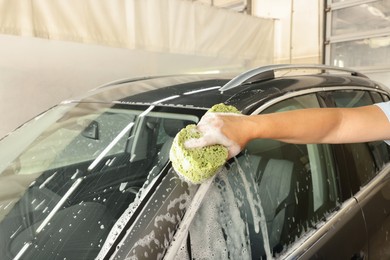 Photo of Man washing auto with sponge at car wash, closeup