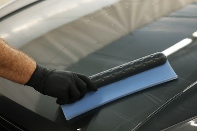 Man wiping auto with squeegee brush at car wash, closeup