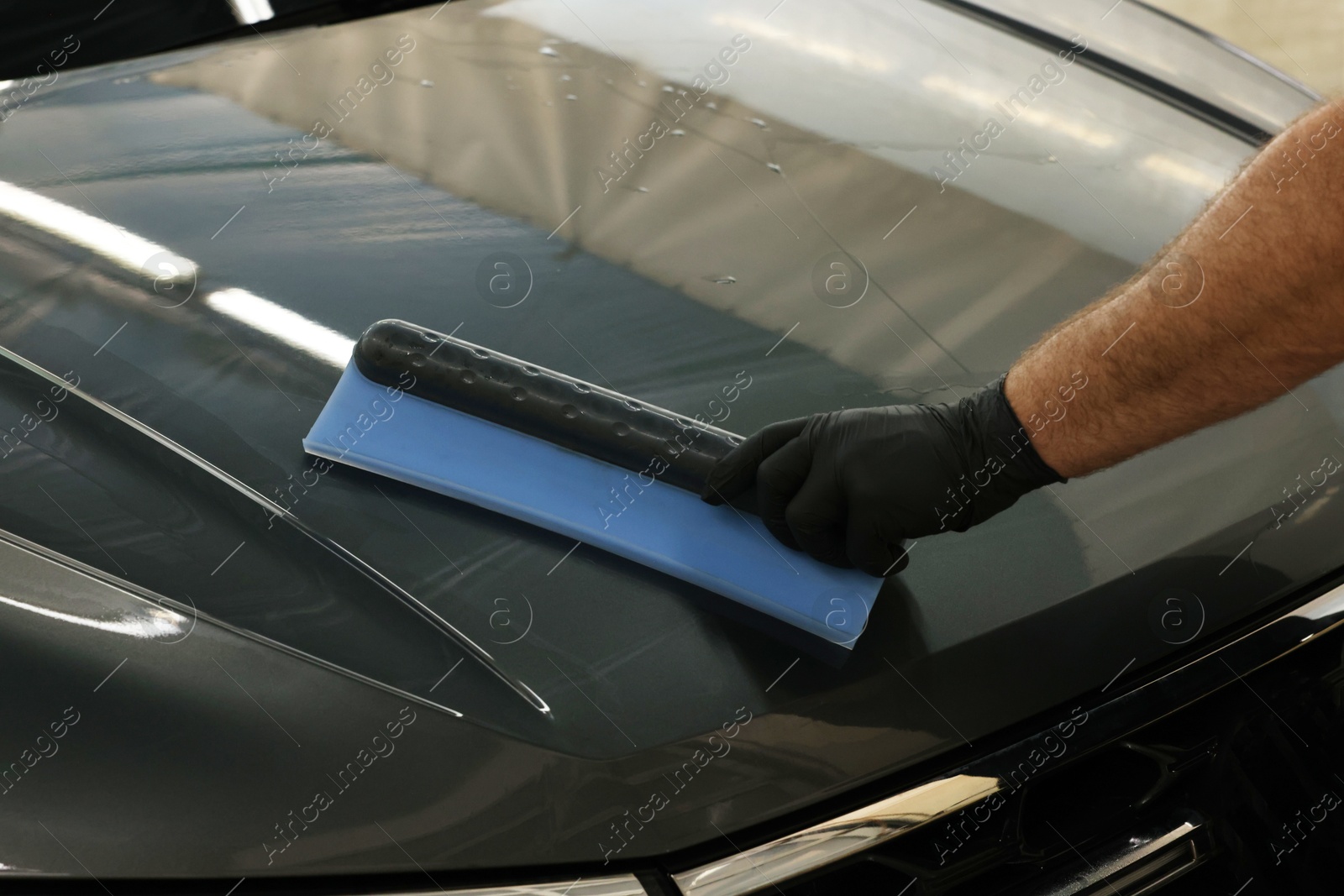 Photo of Man wiping auto with squeegee brush at car wash, closeup