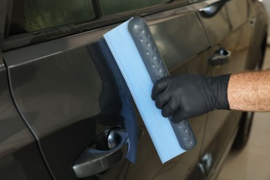 Photo of Man wiping auto with squeegee brush at car wash, closeup