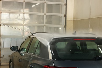 Washing auto with high pressure water jet at car wash, closeup