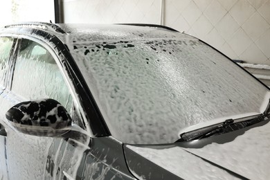 Auto covered with cleaning foam at car wash, closeup