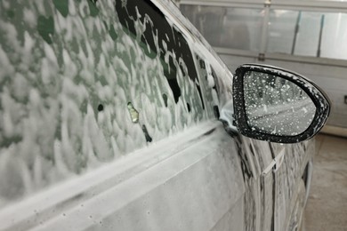 Auto covered with cleaning foam at car wash, closeup