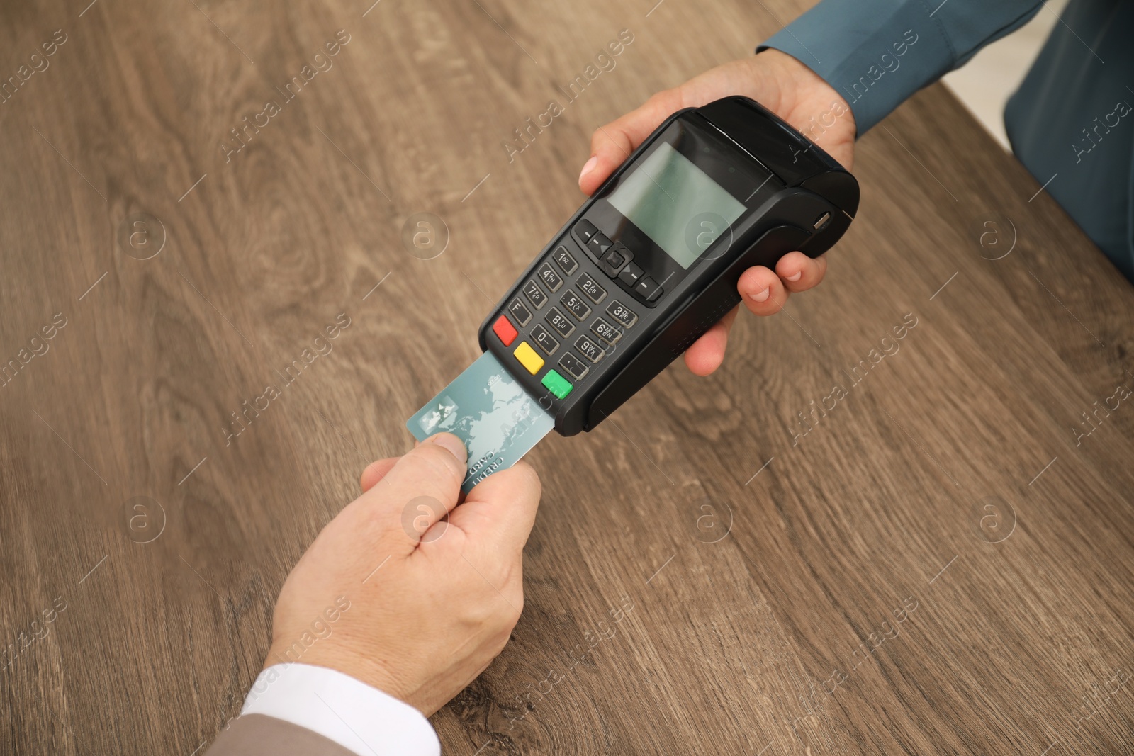 Photo of Woman taking payment from client via credit card terminal at wooden table, closeup