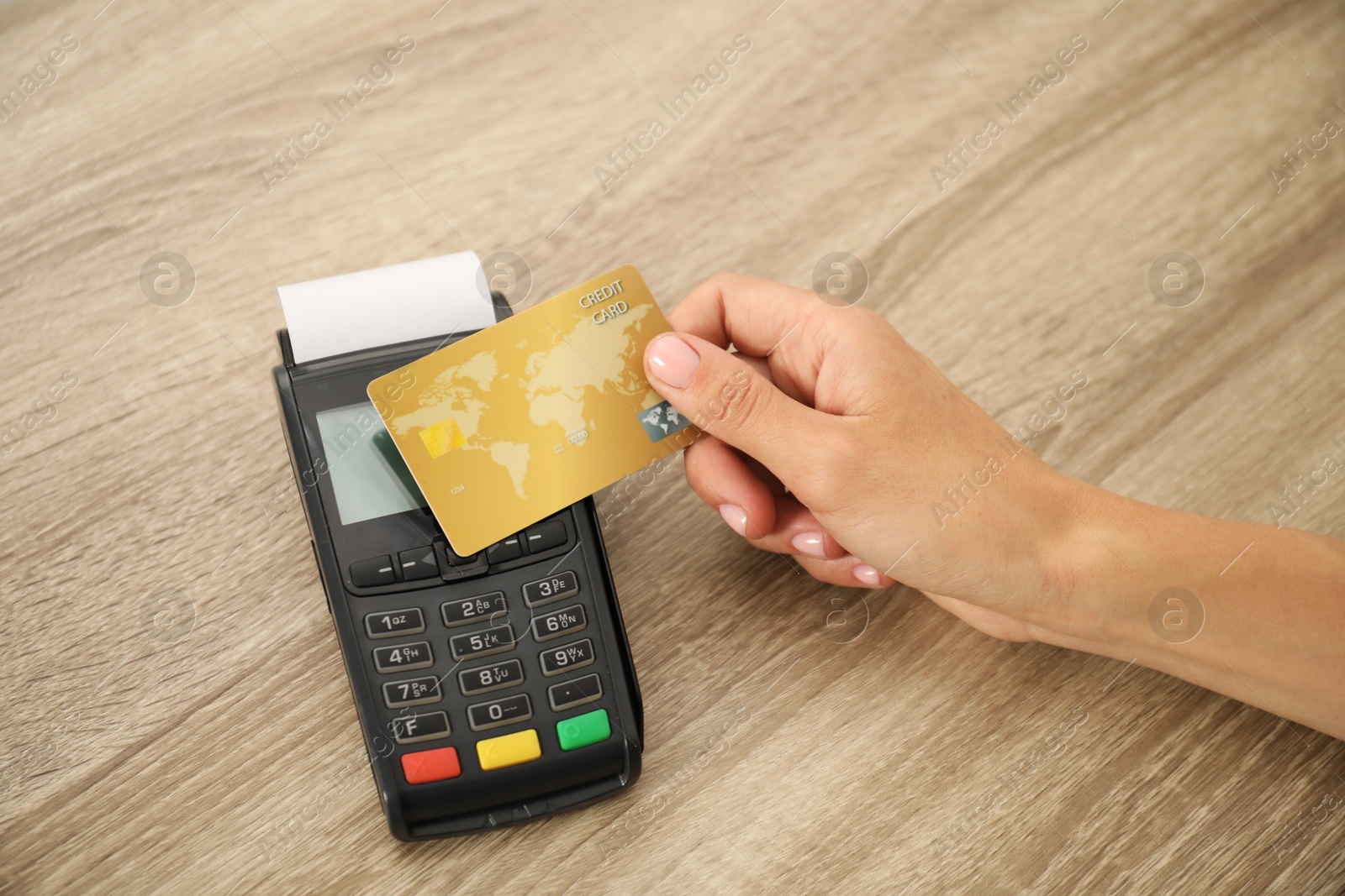 Photo of Woman with credit card using terminal at wooden table, closeup