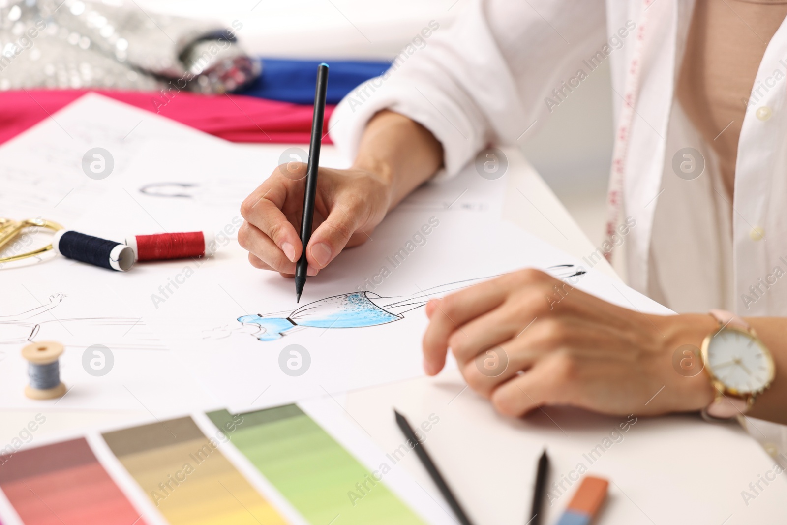 Photo of Fashion designer drawing sketch of dress at table in workshop, closeup