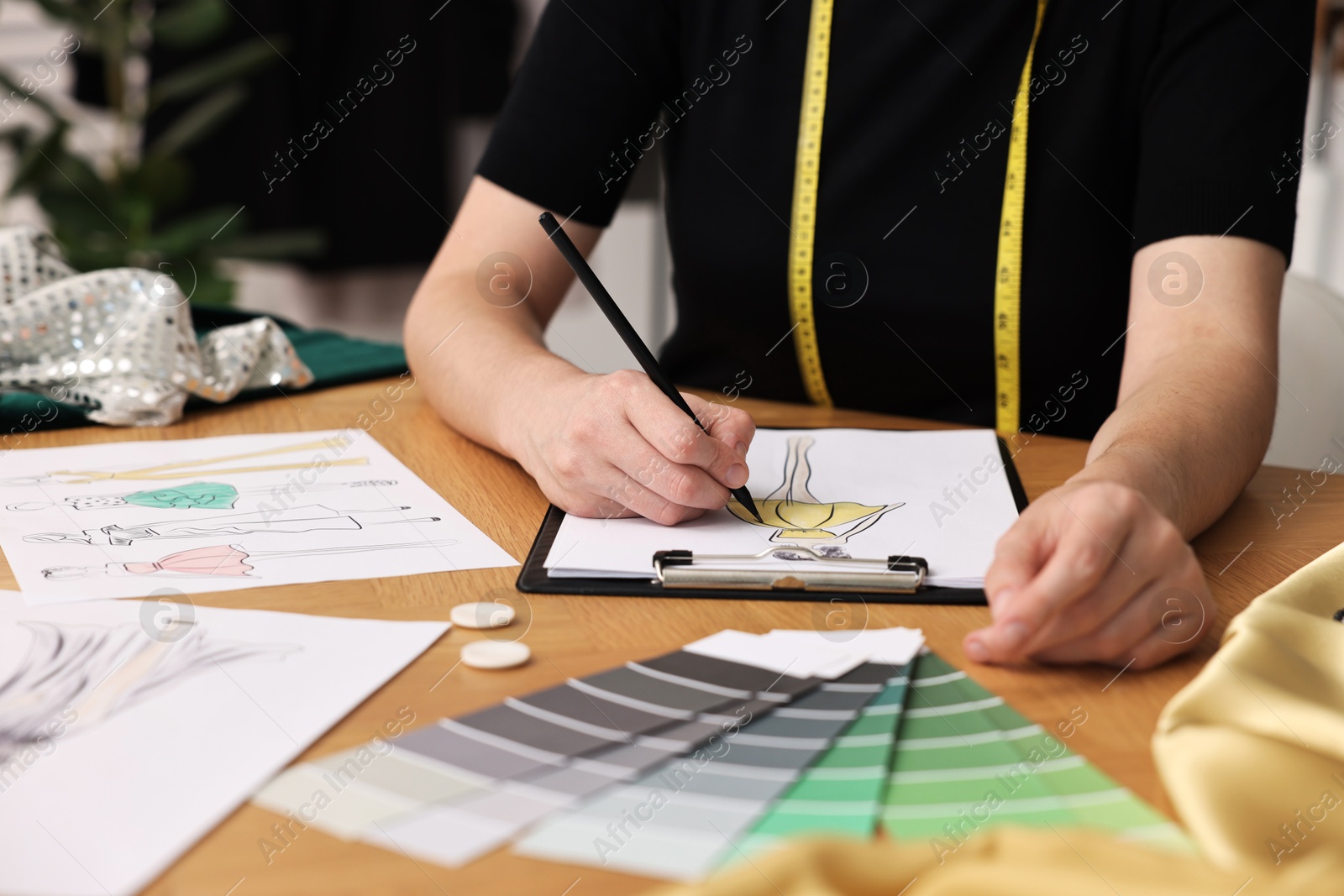 Photo of Fashion designer drawing sketch of beautiful dress at wooden table, closeup