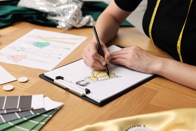 Fashion designer drawing sketch of beautiful dress at wooden table, closeup