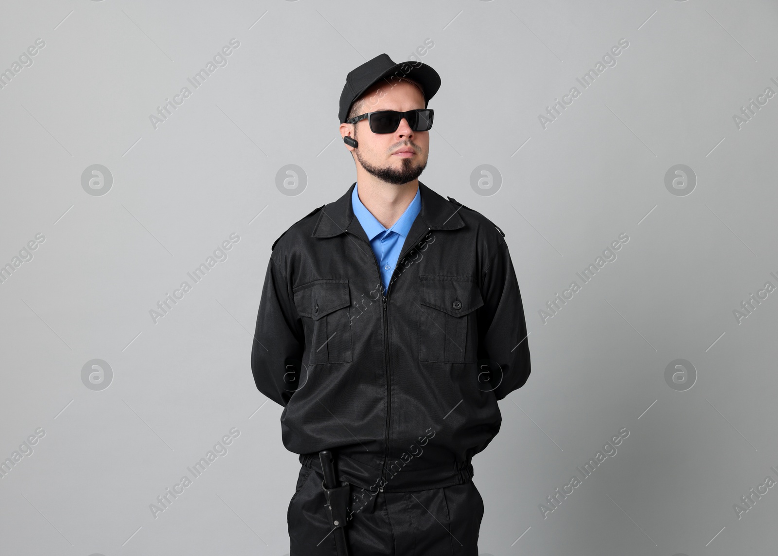 Photo of Security guard in uniform and sunglasses on grey background