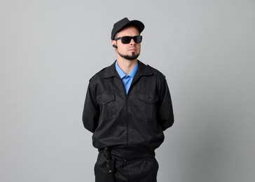 Security guard in uniform and sunglasses on grey background