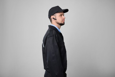 Photo of Security guard in uniform with earpiece on grey background