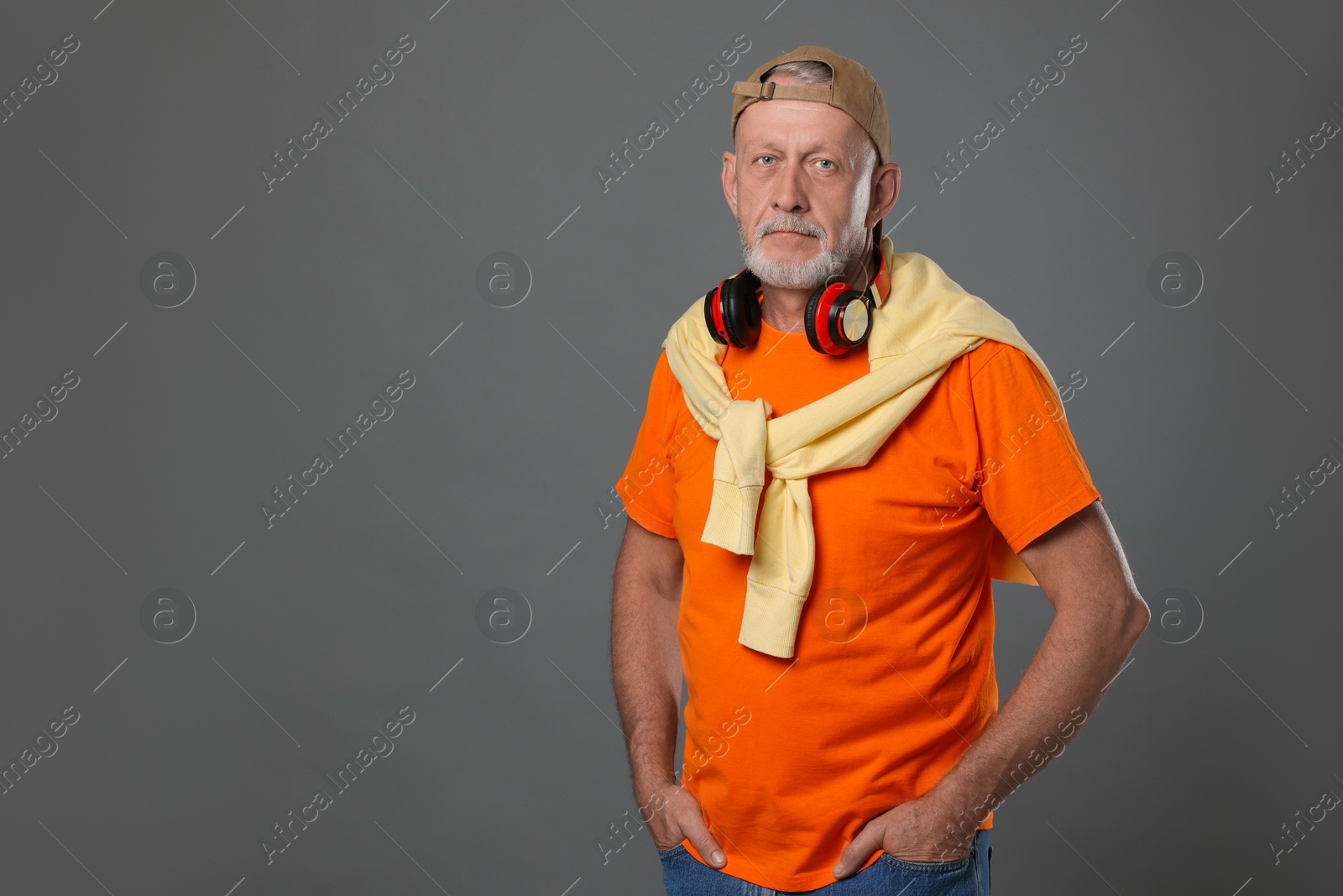 Photo of Portrait of handsome senior man with headphones on grey background. Space for text