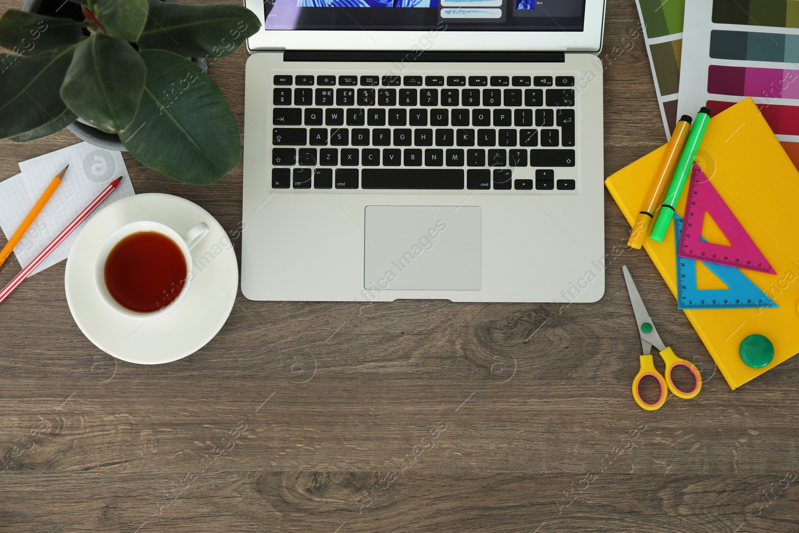 Photo of Fashion designer`s workplace with laptop, cup of tea and different stationery on wooden table, flat lay