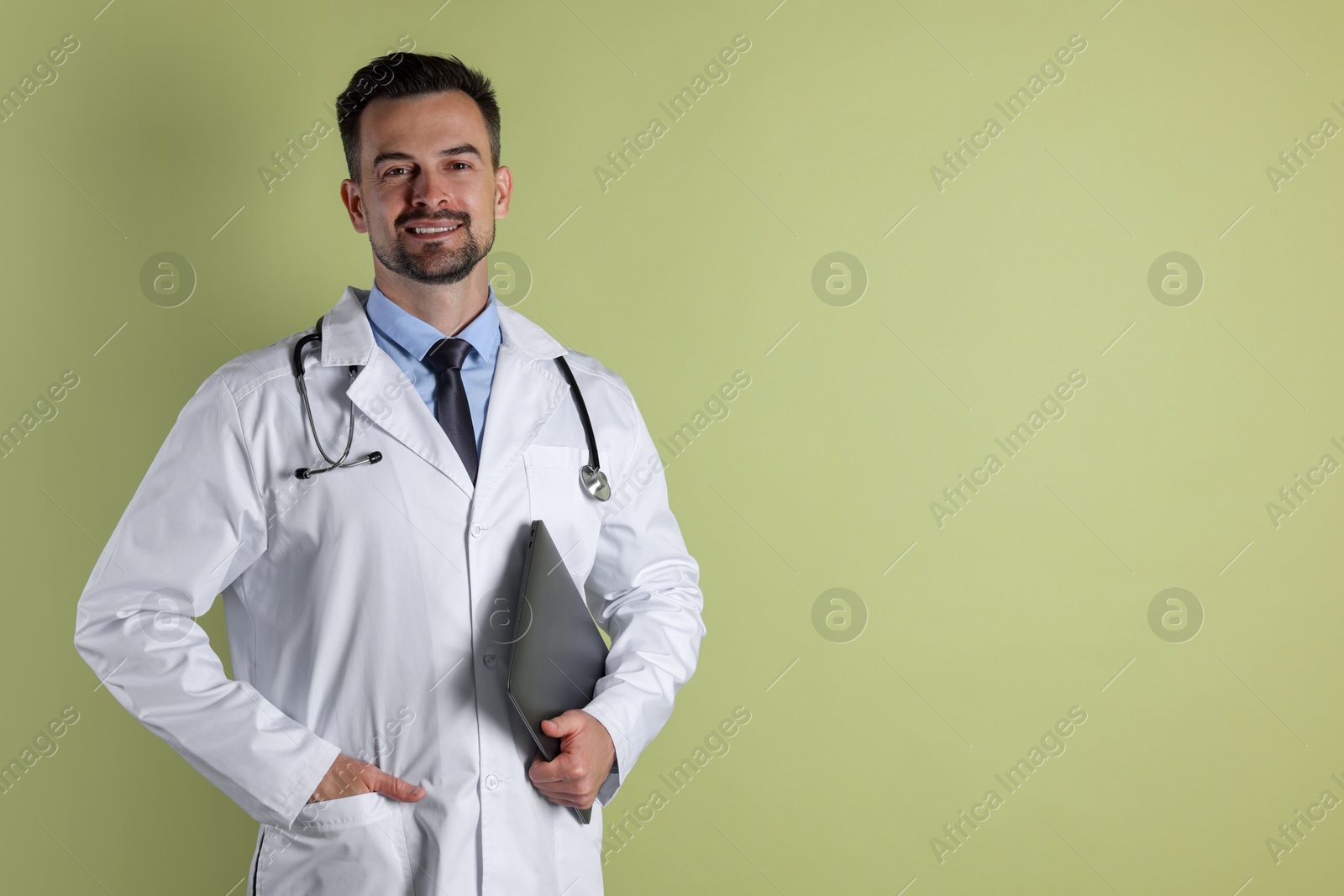 Photo of Smiling doctor with stethoscope and laptop on olive background, space for text