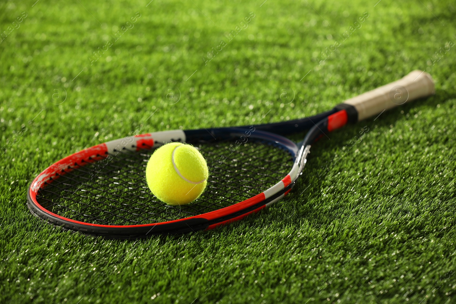 Photo of Tennis racket and ball on green artificial grass