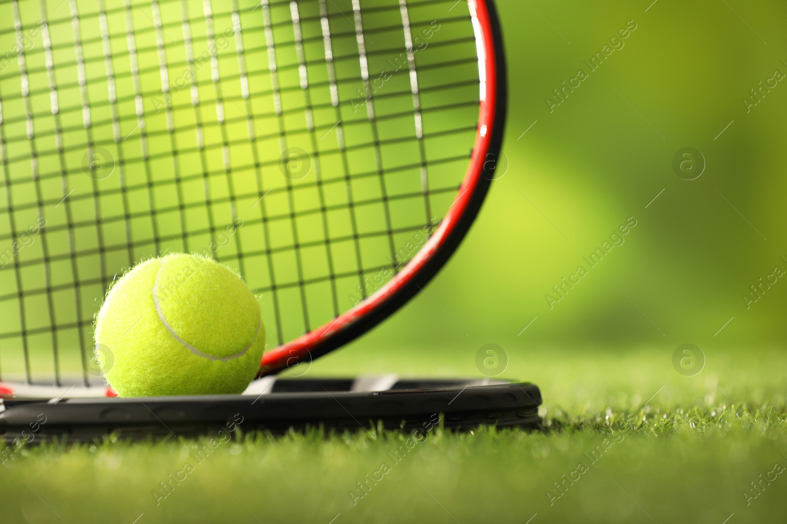 Photo of Tennis rackets and ball on green artificial grass, closeup