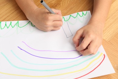 Photo of Boy drawing picture at wooden table, closeup