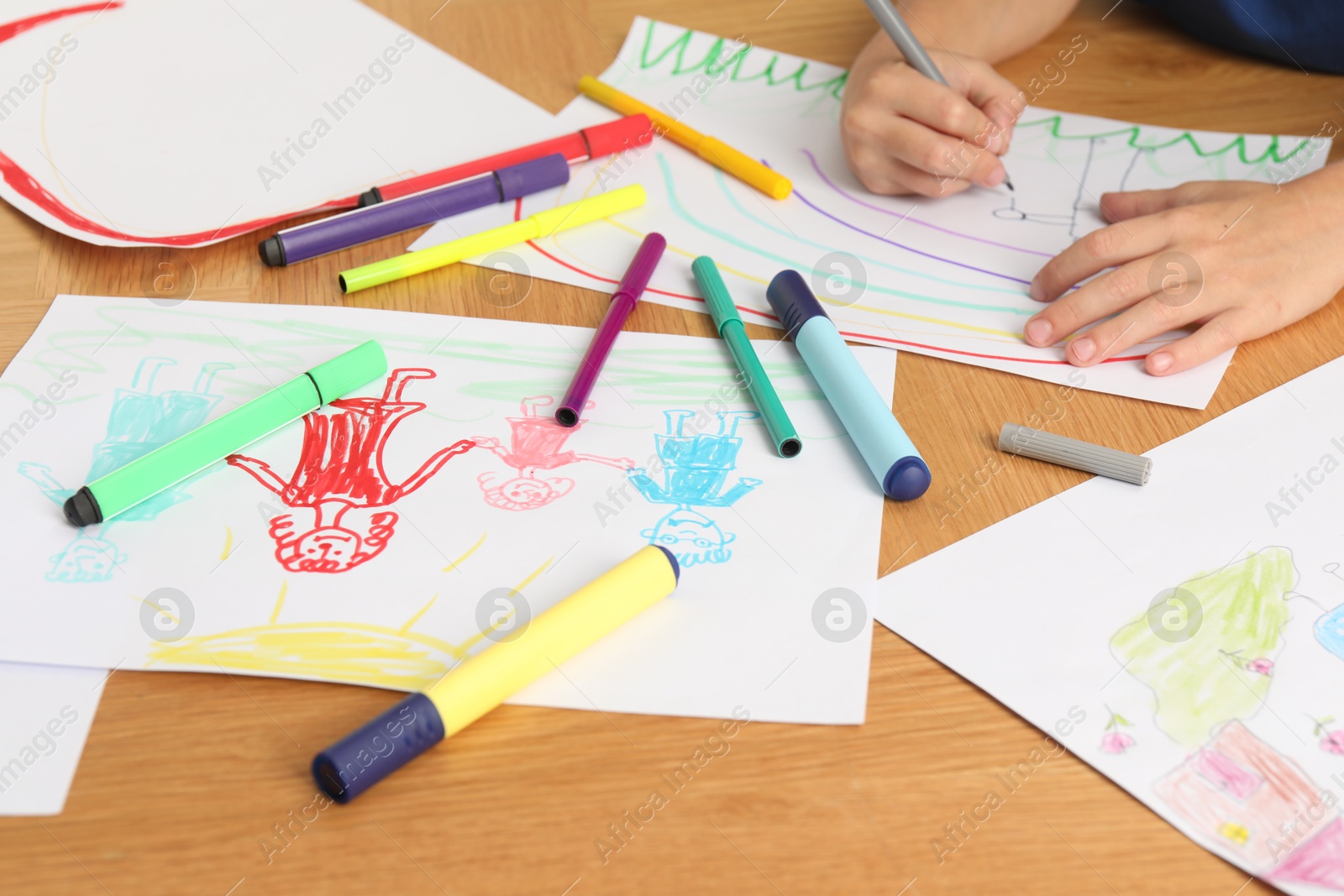 Photo of Boy drawing picture at wooden table, closeup