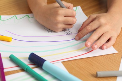 Photo of Boy drawing picture at wooden table, closeup