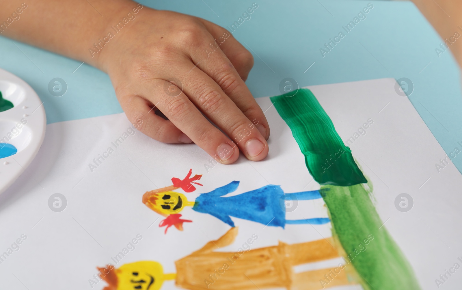 Photo of Boy with picture at light blue table, closeup