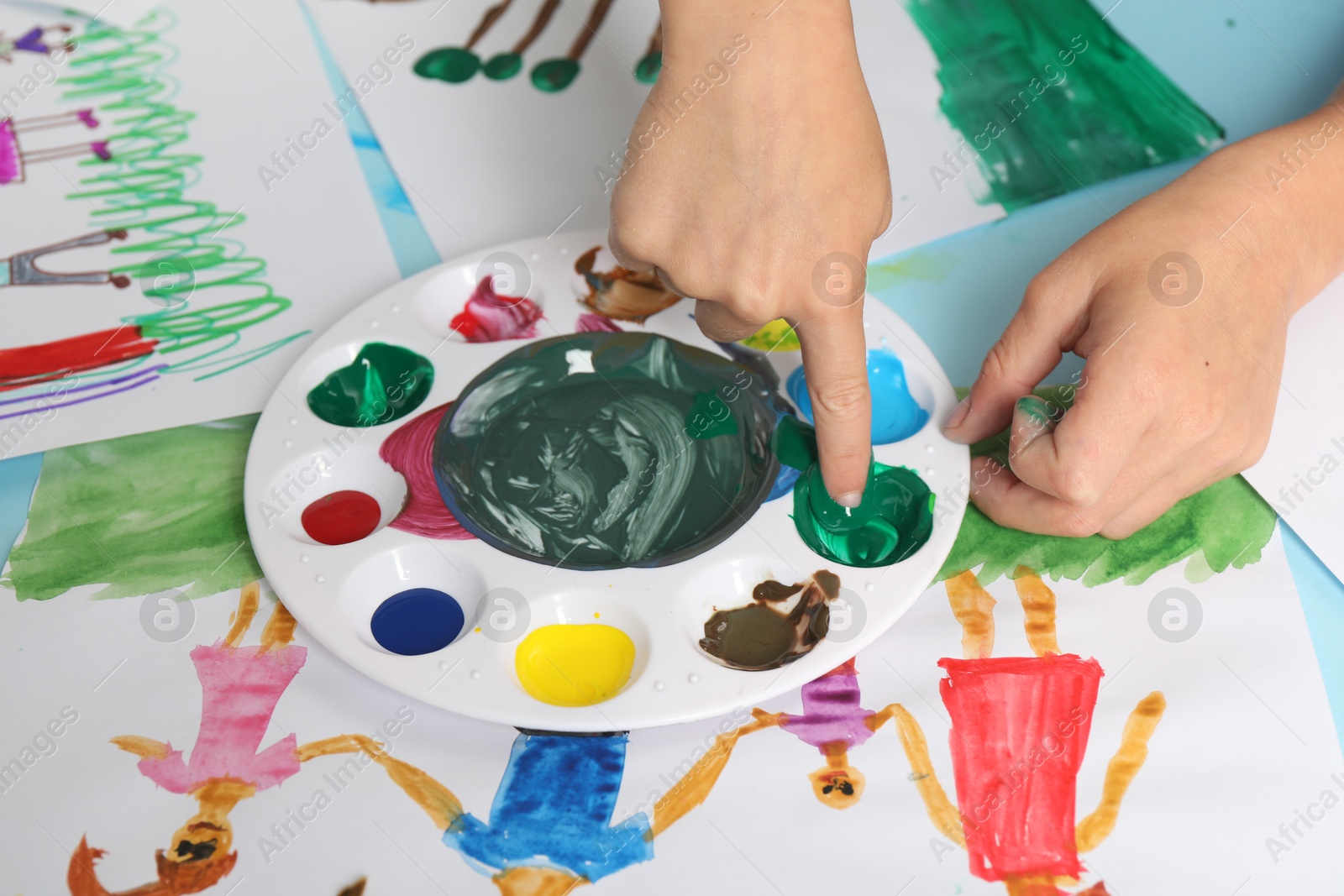 Photo of Boy drawing picture with paint at table, closeup