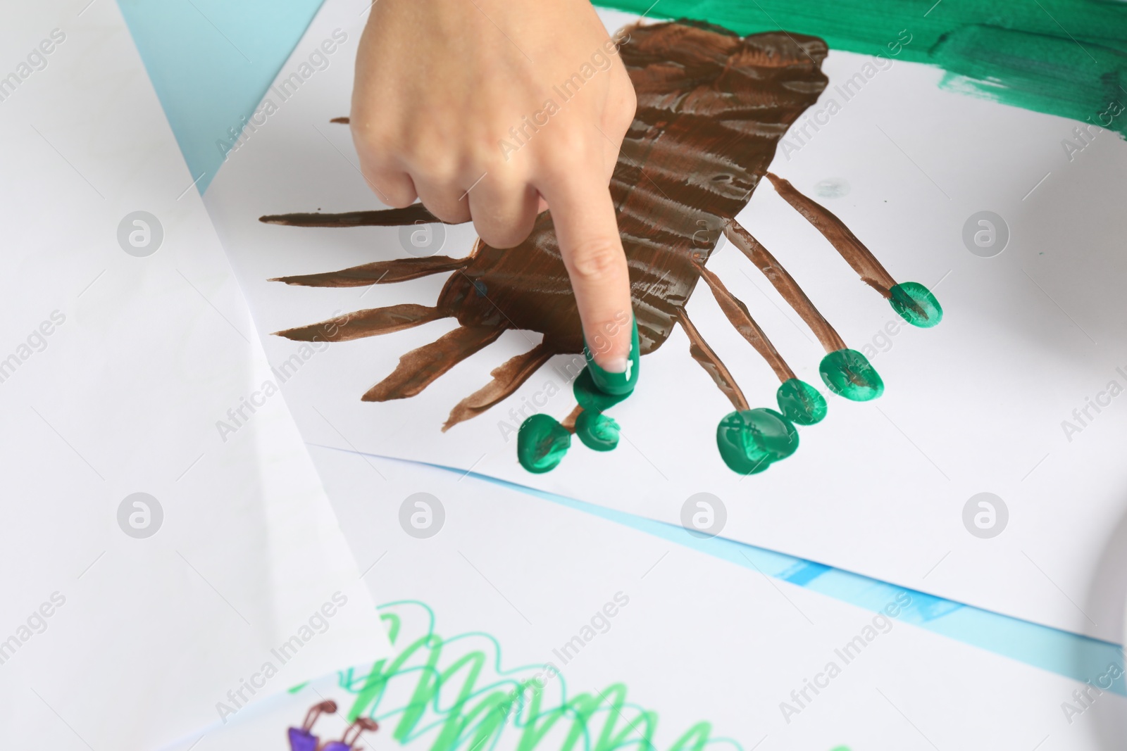 Photo of Boy drawing picture with paint at table, closeup