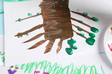 Photo of Boy drawing picture with paint at table, closeup