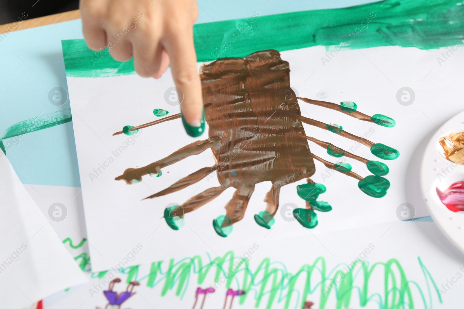 Photo of Boy drawing picture with paint at table, closeup