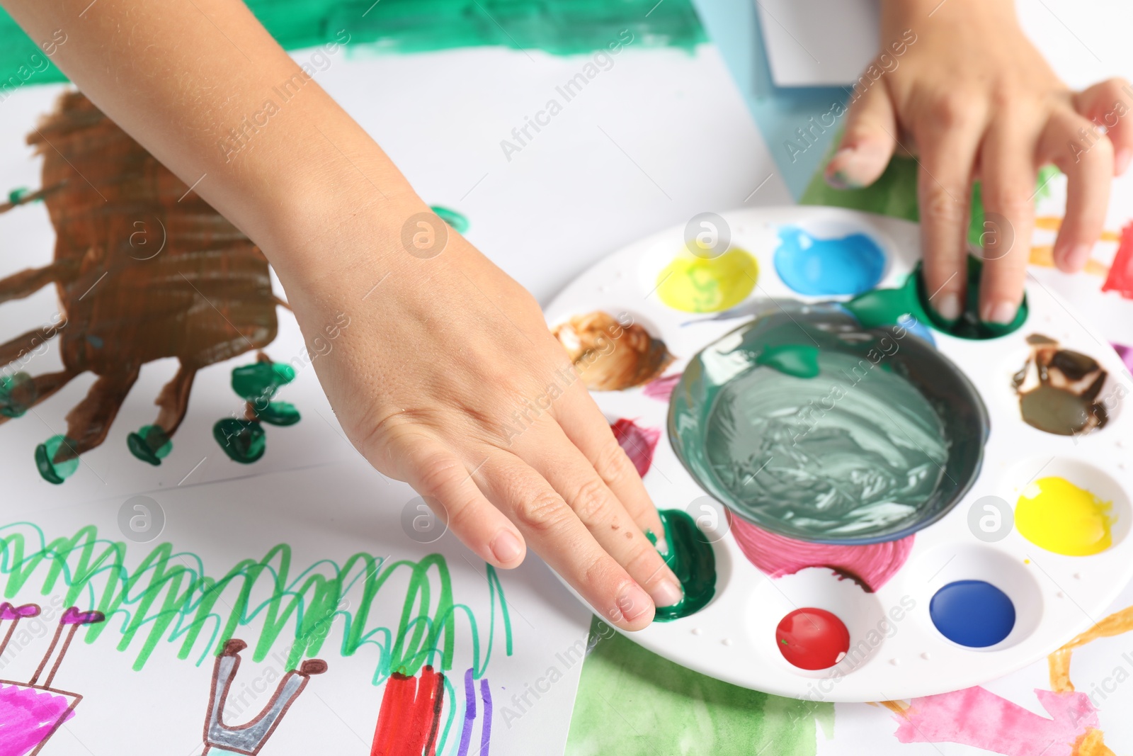 Photo of Boy drawing picture with paint at table, closeup