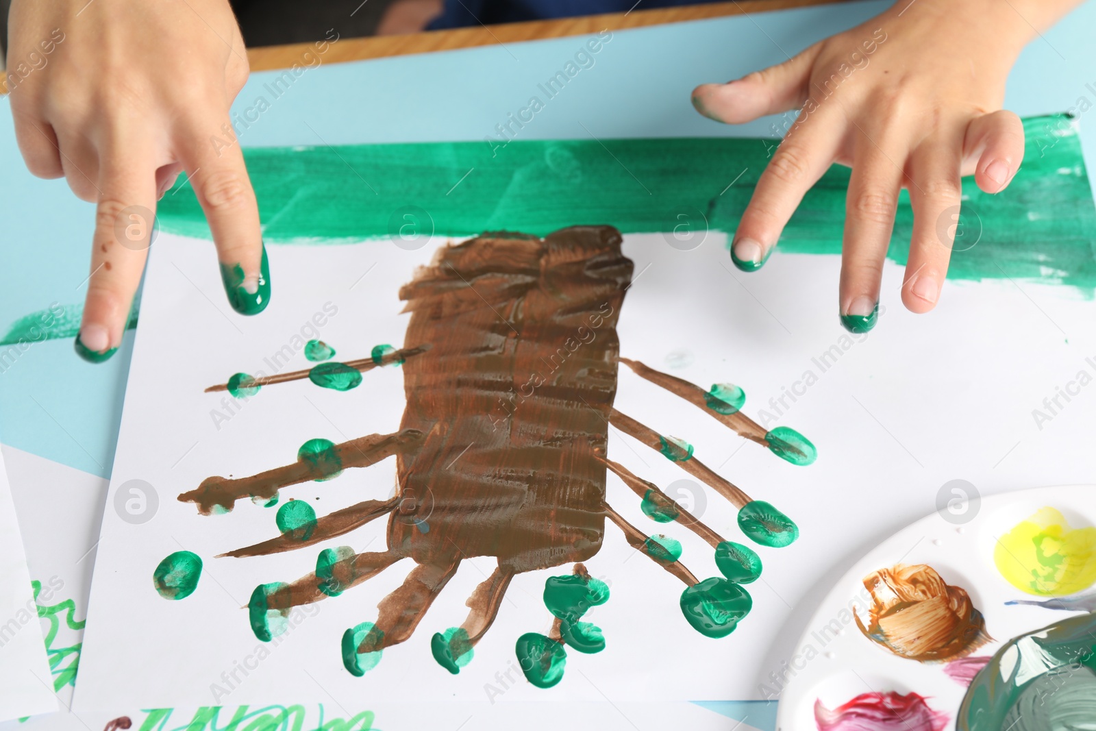 Photo of Boy drawing picture with paint at table, closeup