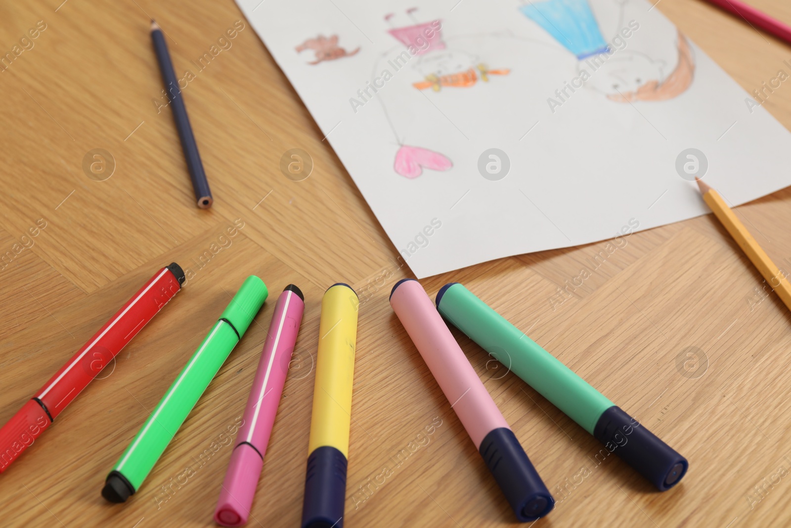 Photo of Child`s picture and felt pens on wooden table, closeup