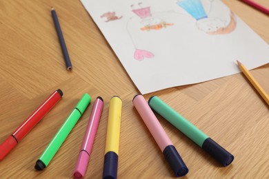 Photo of Child`s picture and felt pens on wooden table, closeup