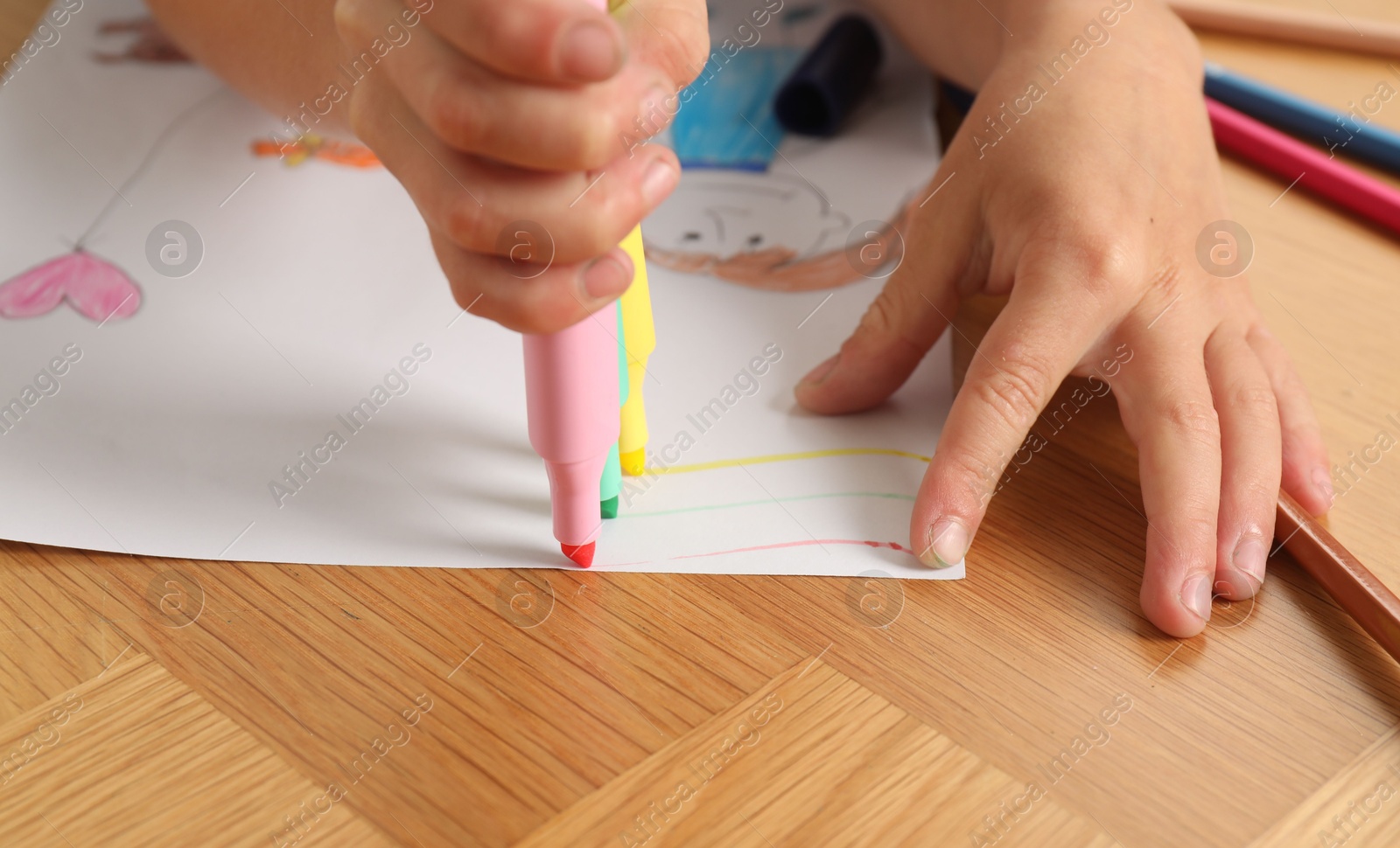 Photo of Boy drawing picture at wooden table, closeup