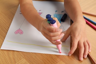 Photo of Boy drawing picture at wooden table, closeup