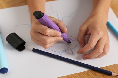 Photo of Boy drawing picture at wooden table, closeup