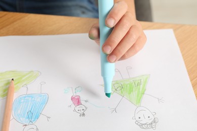 Photo of Boy drawing his family at wooden table, closeup