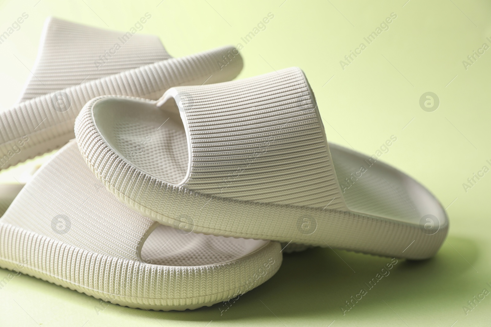 Photo of Three white rubber slippers on green background, closeup