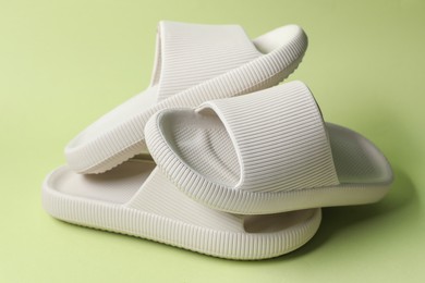 Photo of Three white rubber slippers on green background