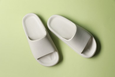 Pair of slippers on green background, top view