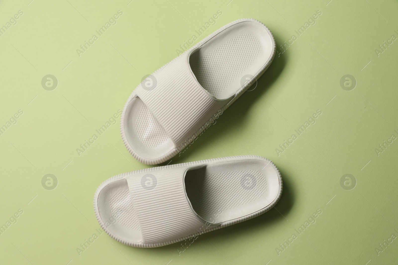 Photo of Pair of slippers on green background, top view