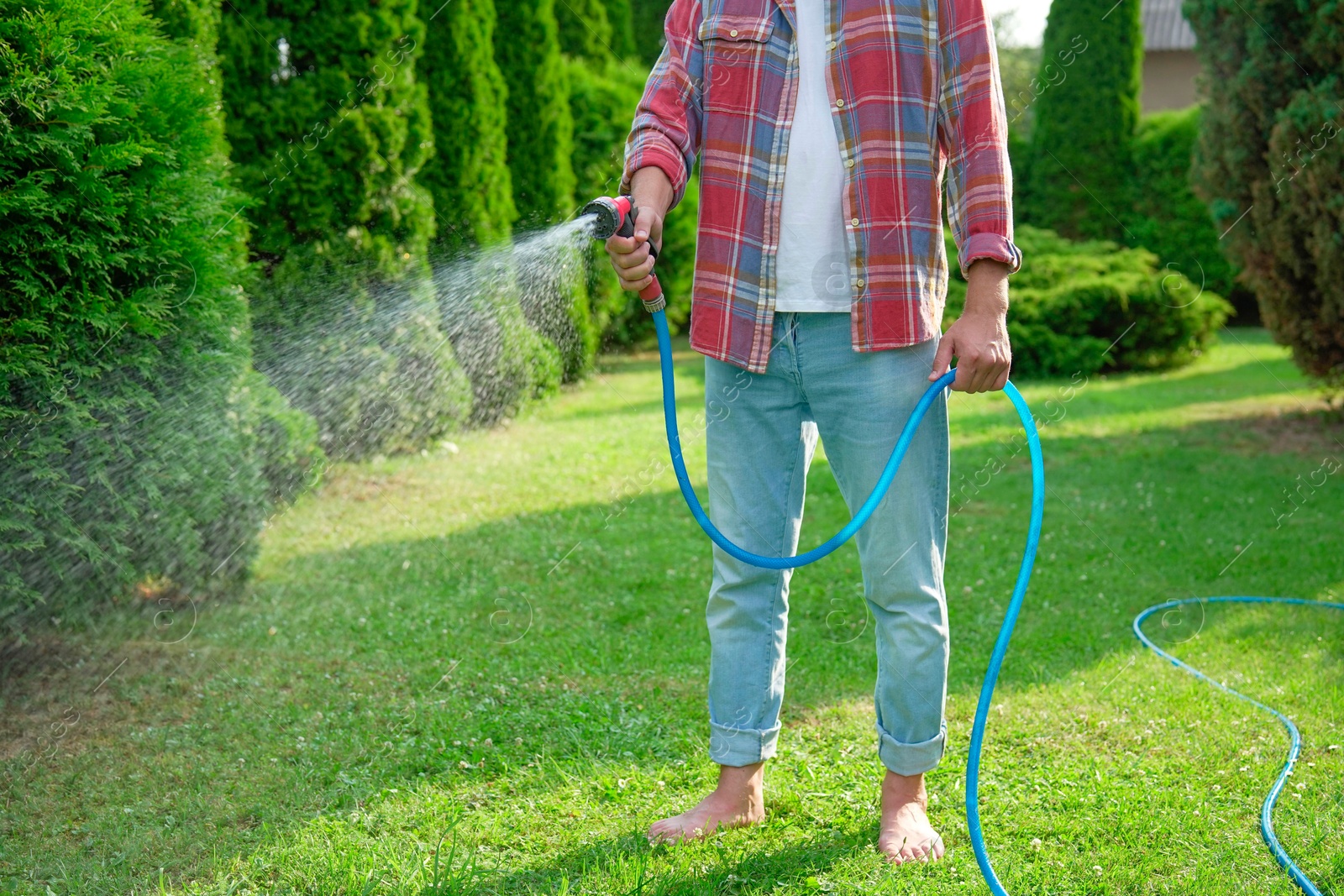 Photo of Man watering lawn with hose in backyard, closeup