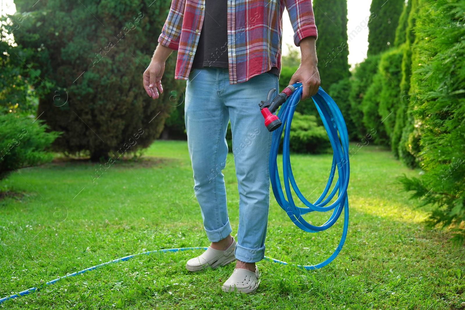 Photo of Man holding watering hose with sprinkler in garden, closeup