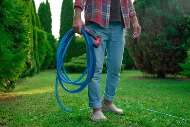 Man holding watering hose with sprinkler in garden, closeup