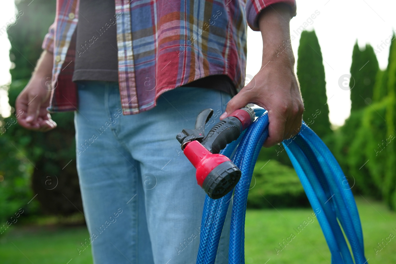 Photo of Man holding watering hose with sprinkler in garden, closeup