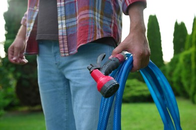 Photo of Man holding watering hose with sprinkler in garden, closeup