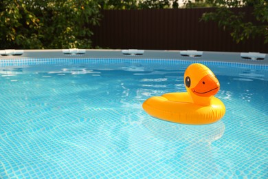 Photo of Inflatable duck shaped ring on water in above ground swimming pool outdoors, space for text