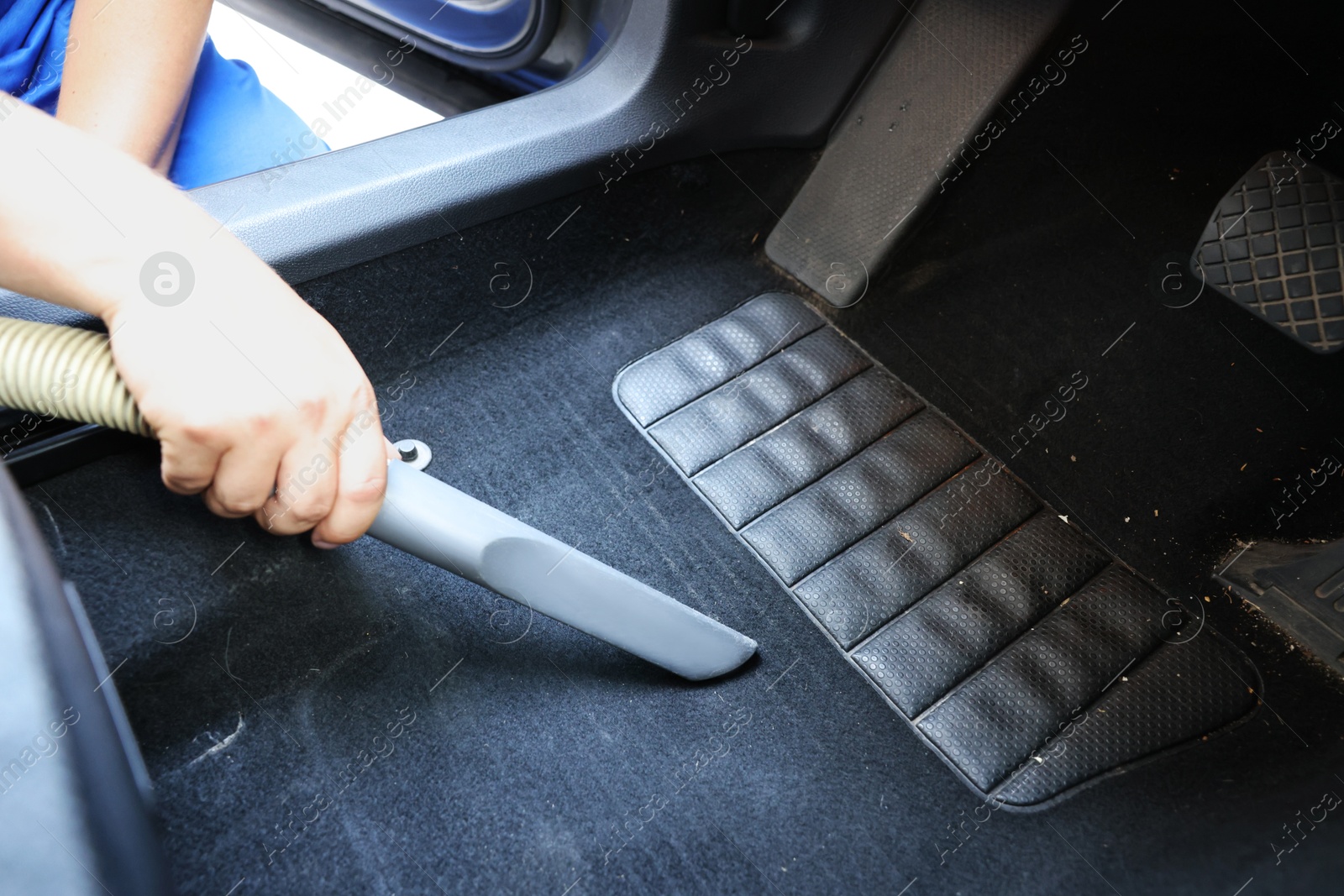 Photo of Man cleaning car floor mat with vacuum cleaner, closeup